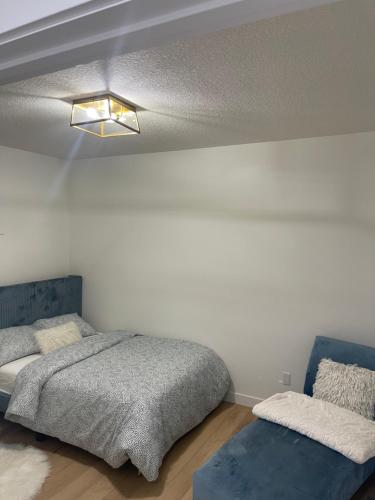 埃德蒙顿Stylish 2 Bedroom suite in SW Edmonton close to Windermere and Edmonton International Airport的一间卧室配有一张床和一张蓝色的沙发