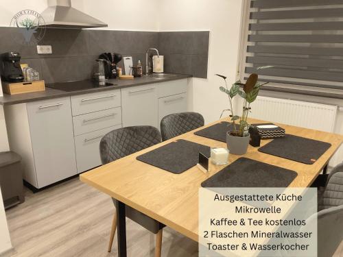 皮尔马森斯Stierpartment am Pfälzer Wald nähe Outlet Center Zweibrücken的厨房配有木桌和椅子