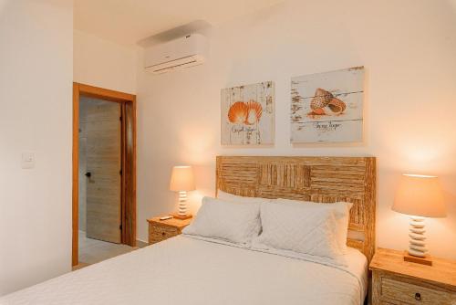 蓬塔卡纳Cerca de la playa con piscina y gimnasio的卧室配有白色的床和两盏灯。