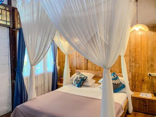 WainapalKrui Surfing的卧室配有白色天蓬床和蓝色窗帘