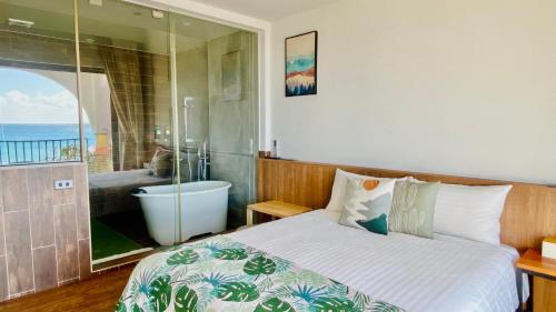南湾觅夏旅店的一间卧室配有一张床,浴室设有浴缸