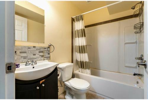 卡尔加里Akeem的浴室配有盥洗盆、卫生间和浴缸。