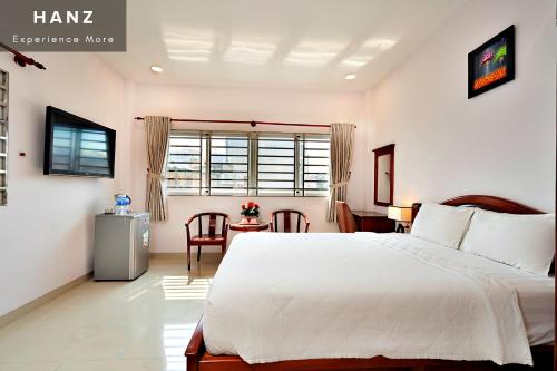 胡志明市HANZ Hoang Hoang Hotel Ben Thanh的卧室配有一张白色的大床和一张桌子