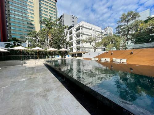 曼谷Floral Court Hotel & Residence Sukhumvit 13的城市里带遮阳伞的水池
