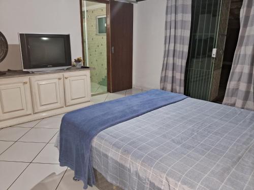 里约达欧特拉斯Casa da Praia em Costazul的一间卧室配有电视和一张带蓝色毯子的床。