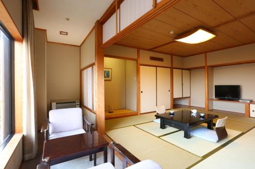 神户莫托玉克斯恩卡库日式旅馆的客厅配有桌椅和电视。