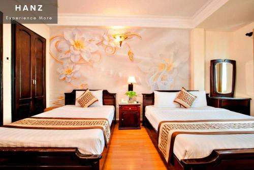胡志明市HANZ Thanh Thu Hotel的一间卧室设有两张床和鲜花墙