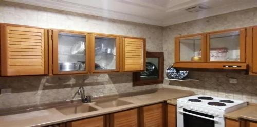 吉达حياة ريف للوحدات السكنية المفروشة的厨房配有木制橱柜和白色炉灶。