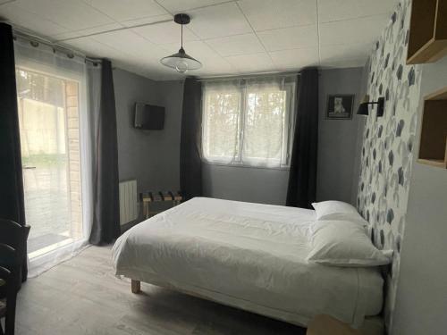 勒芒Cabane du Circuit的卧室配有白色的床和2扇窗户。