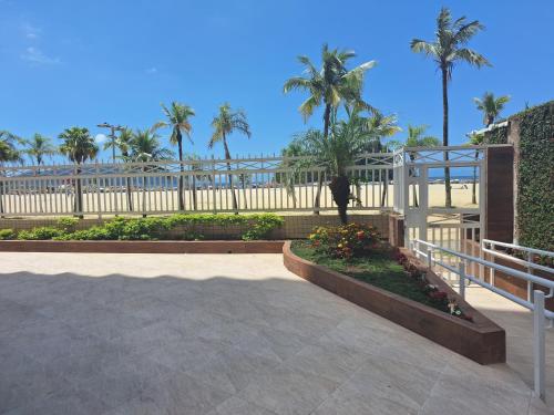 桑托斯Aqui é pé na areia的一个带棕榈树和白色围栏的庭院