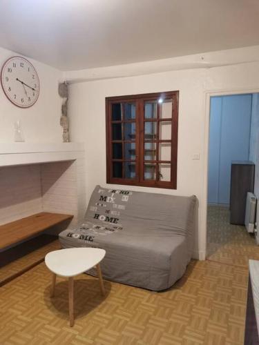 欧里亚克T1 bis centre ville d'Aurillac的客厅配有一张床和墙上的时钟