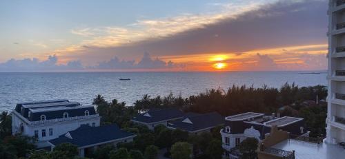 富国HAYA Sea View Hotel Phu Quoc的水面上的日落,房屋和建筑