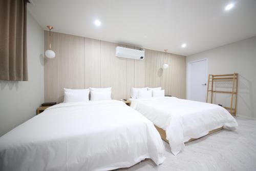 昌原市HARU Hotel的配有白色床单的客房内的两张床