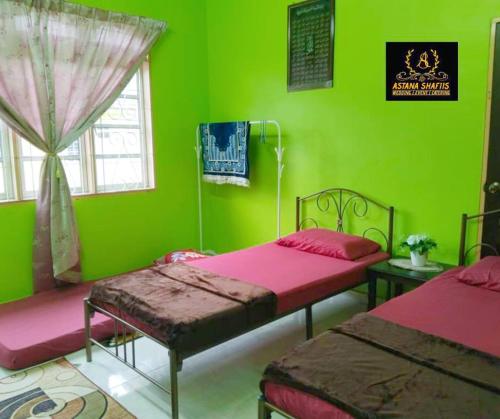 马六甲ASTANA SHAFIIS的绿色的客房设有两张床和窗户。