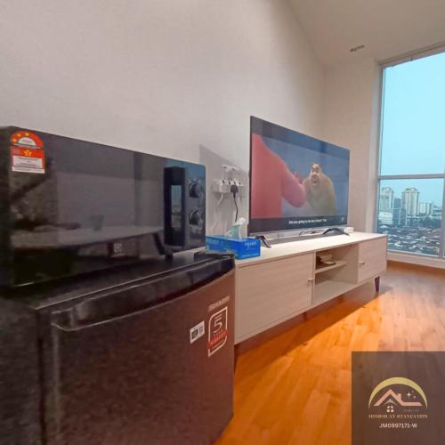峇六拜Minimalist Duplex @ BayanLepas的客厅配有平面电视和桌子。