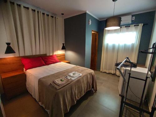 圣若热岛Vitória Suítes - Vila de São Jorge的一间卧室配有一张带红色枕头的床和一扇窗户