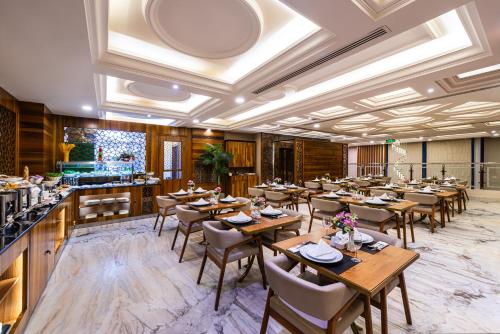 利雅德Crown Rose AlSahafa Hotel的一间带木桌椅的餐厅和一间酒吧