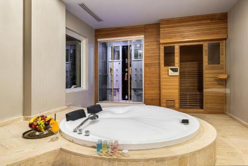 利雅德Crown Rose AlSahafa Hotel的带淋浴的浴室内的白色大浴缸