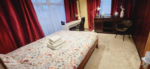 德罗赫达Fox Lodge的一间卧室配有一张带红色窗帘的床和一张书桌