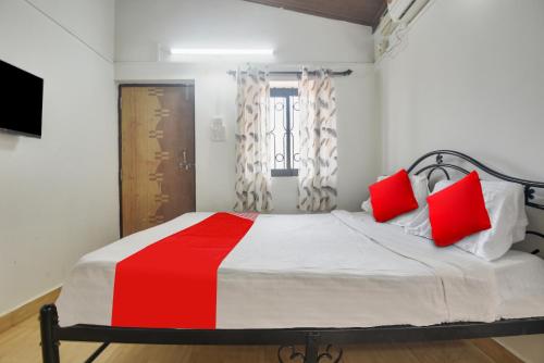 巴加OYO Pratisha Guest House的一间卧室配有一张带红色枕头的大床