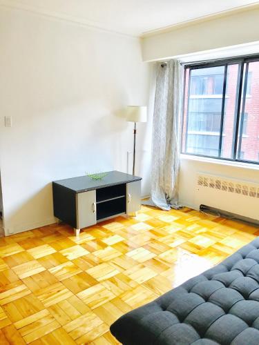 蒙特利尔Stylish Montreal Apartment: Comfortable Stay in the Golden Square Mile的客厅铺有木地板,配有沙发。