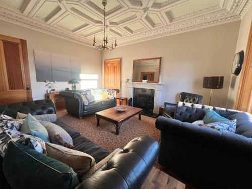 卡诺斯蒂Morven Guest House Carnoustie的客厅配有皮革家具和格子天花板