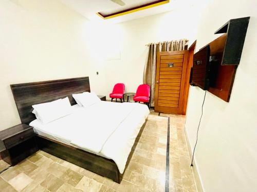 卡拉奇Airport Hotel Bed & Rest的一间卧室配有一张床和两张红色椅子