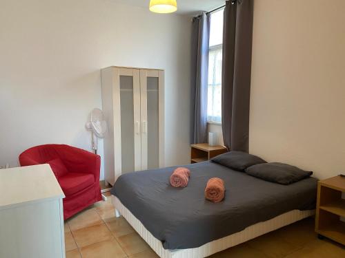 滨海苏拉克Appartement familial centre et plage的一间卧室配有一张床和一张红色椅子