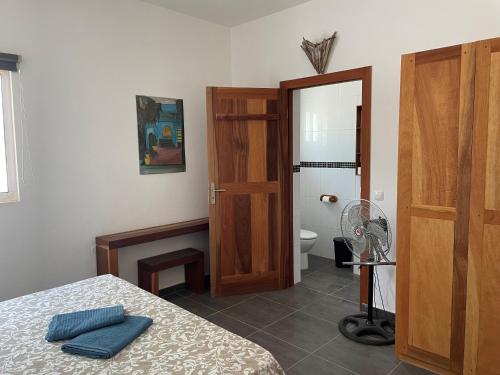 马约城Villa Sol e Mar - Vila do Maio - Ponta Preta的一间带一张床的卧室和一间带风扇的浴室