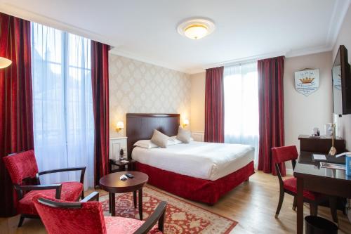 布尔日Best Western Plus Hôtel D'Angleterre的酒店客房,配有一张床、一张桌子和椅子