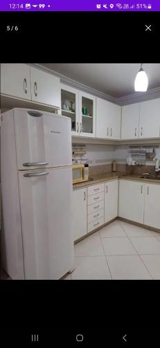 多明戈斯马丁斯Apartamento a 2 Minutos da Praça!的厨房配有白色橱柜和白色冰箱。