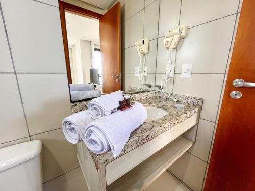 纳塔尔Janastí Suítes Praia de Ponta Negra的浴室配有盥洗盆、镜子和毛巾