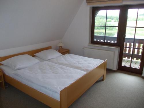马尔洛Finnhäuser am Vogelpark - Haus Brigitte的一间卧室配有一张带白色床单的床和一扇窗户。