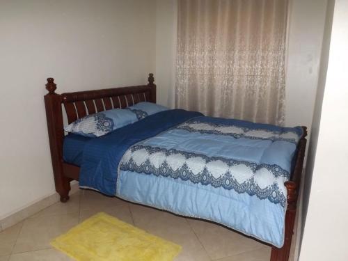坎帕拉Malaika Furnished Apartments的卧室内的一张带蓝色棉被和枕头的床