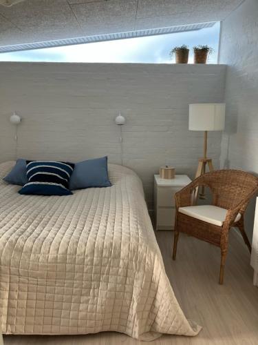 维斯特罗哈文GuestHouse Læsø的一间卧室配有一张床、一把椅子和一盏灯