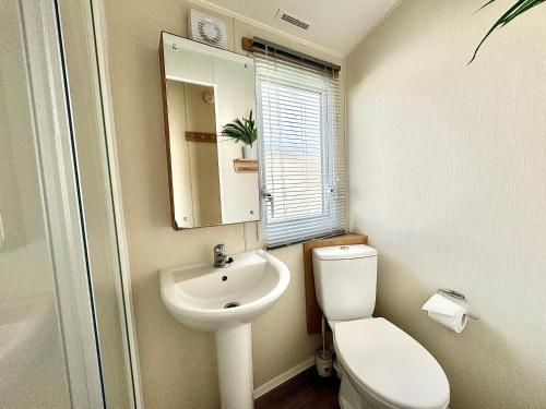 滨海凯斯特Haven Seashore Holiday Park的一间带水槽、卫生间和镜子的浴室