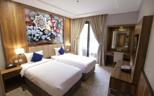 吉达EWG Golden Sea Hotel Obhur的酒店客房设有两张床,墙上挂有绘画作品