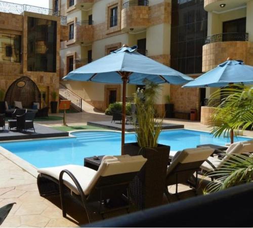 吉达EWG Golden Sea Hotel Obhur的一座带椅子和遮阳伞的游泳池位于一座建筑旁边