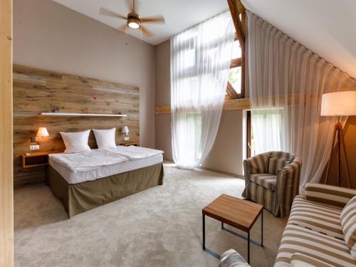 卡罗维发利Cihelny Golf & Wellness Resort的一间卧室配有一张床、一张沙发和一把椅子