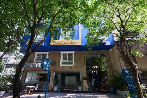 胡志明市La Palma Boutique Hotel的前面有树木的蓝色建筑