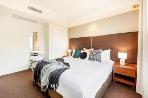 达尔文Poolside Resort Living on Esplanade with Balcony的卧室配有白色大床和木制床头板