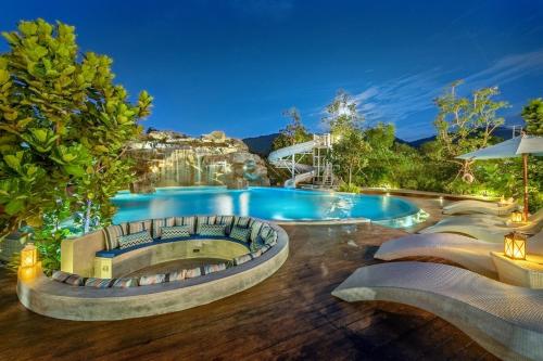 华欣Phukalini Luxury Pool Villa & Onsen-SHA Plus Certified的周围设有大型游泳池,配有椅子