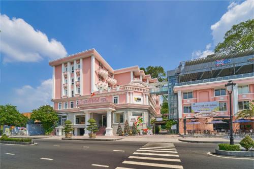 土龙木市Bcons Riverside Hotel Binh Duong的街道边的粉红色建筑