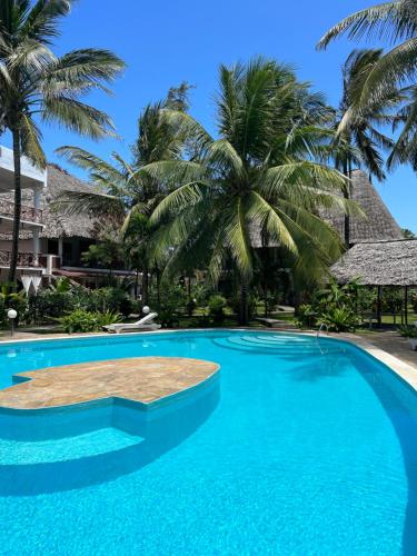 瓦塔穆Watamu Ascot Hotel的一座棕榈树环绕的游泳池