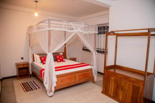 陶尔佩Eden Sea View的一间卧室配有一张带红色枕头的天蓬床