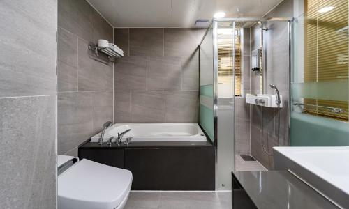 晋州市Golden Tulip Essential Namgang的带浴缸、卫生间和盥洗盆的浴室
