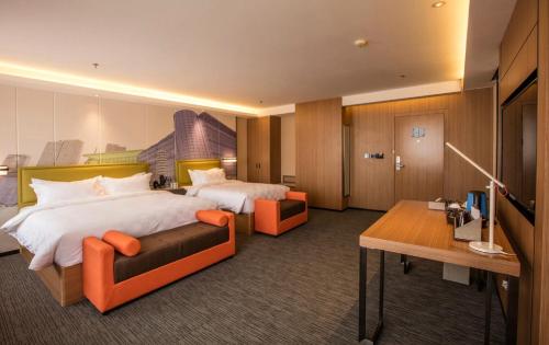 大连美丽豪大连高新万达广场星海酒店的酒店客房配有两张床和一张书桌