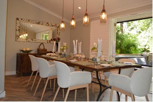 利隆圭Green Elephant的一间带长桌和白色椅子的用餐室