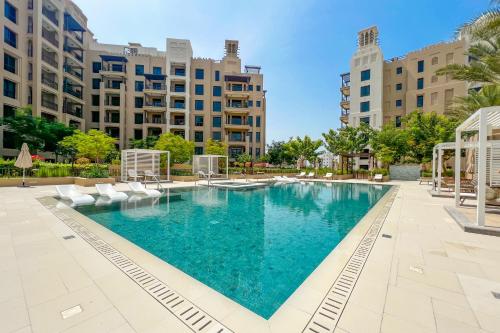 迪拜FAM Living - Serene 1BR Haven in Madinat Jumeirah Living的一个带椅子的游泳池以及位于后面的建筑
