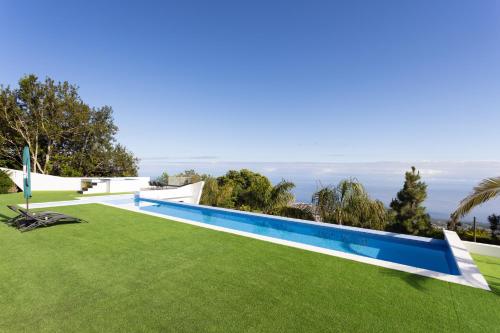 拉奥罗塔瓦Home2Book Stunning Loft Seaviews Finca La Golosa的绿色草地庭院中的游泳池